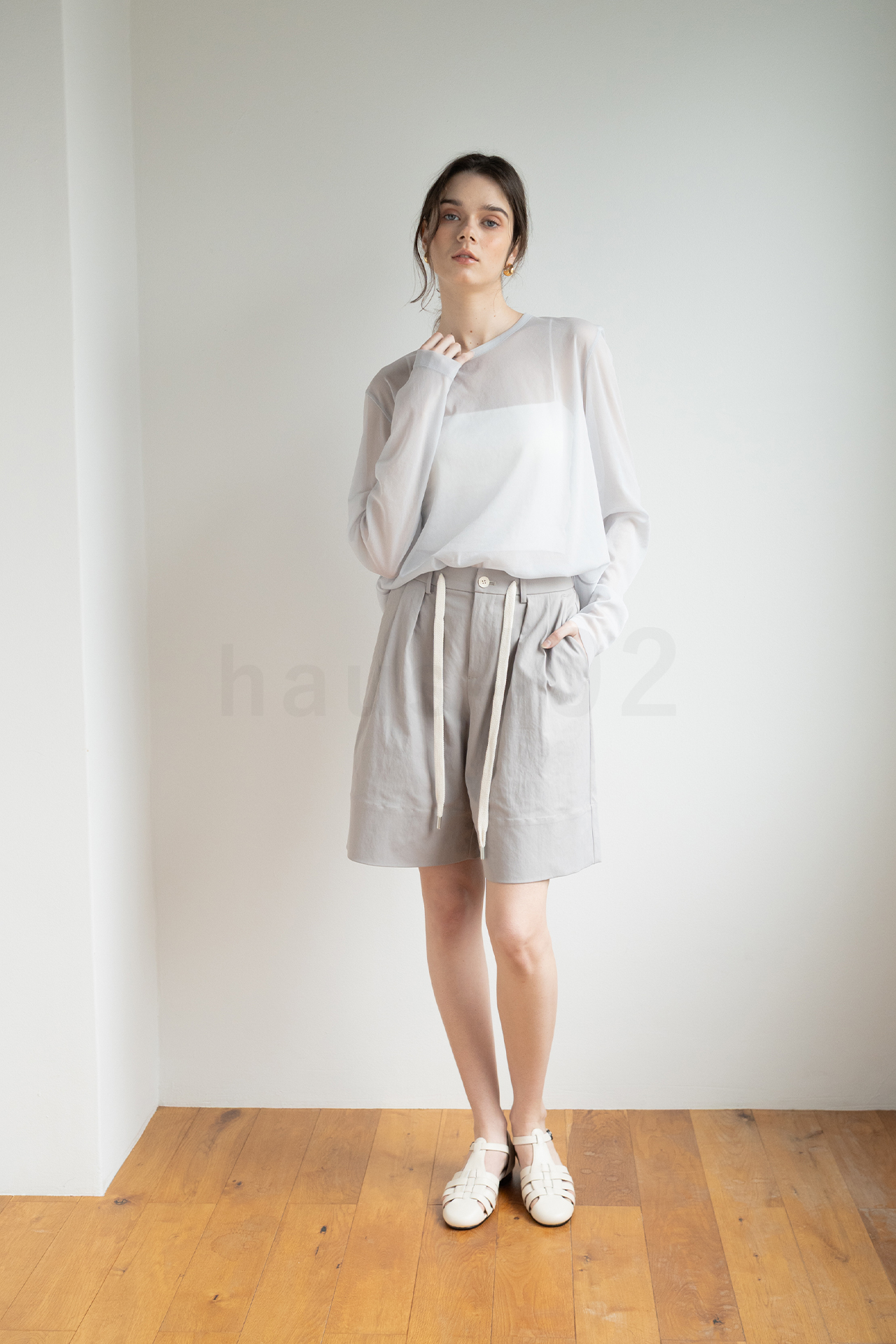 haus402で窓に面した白い壁のすぐ近くにモデルが立った、光を全体に回り込ませて、顔や服の影を優しくした写真